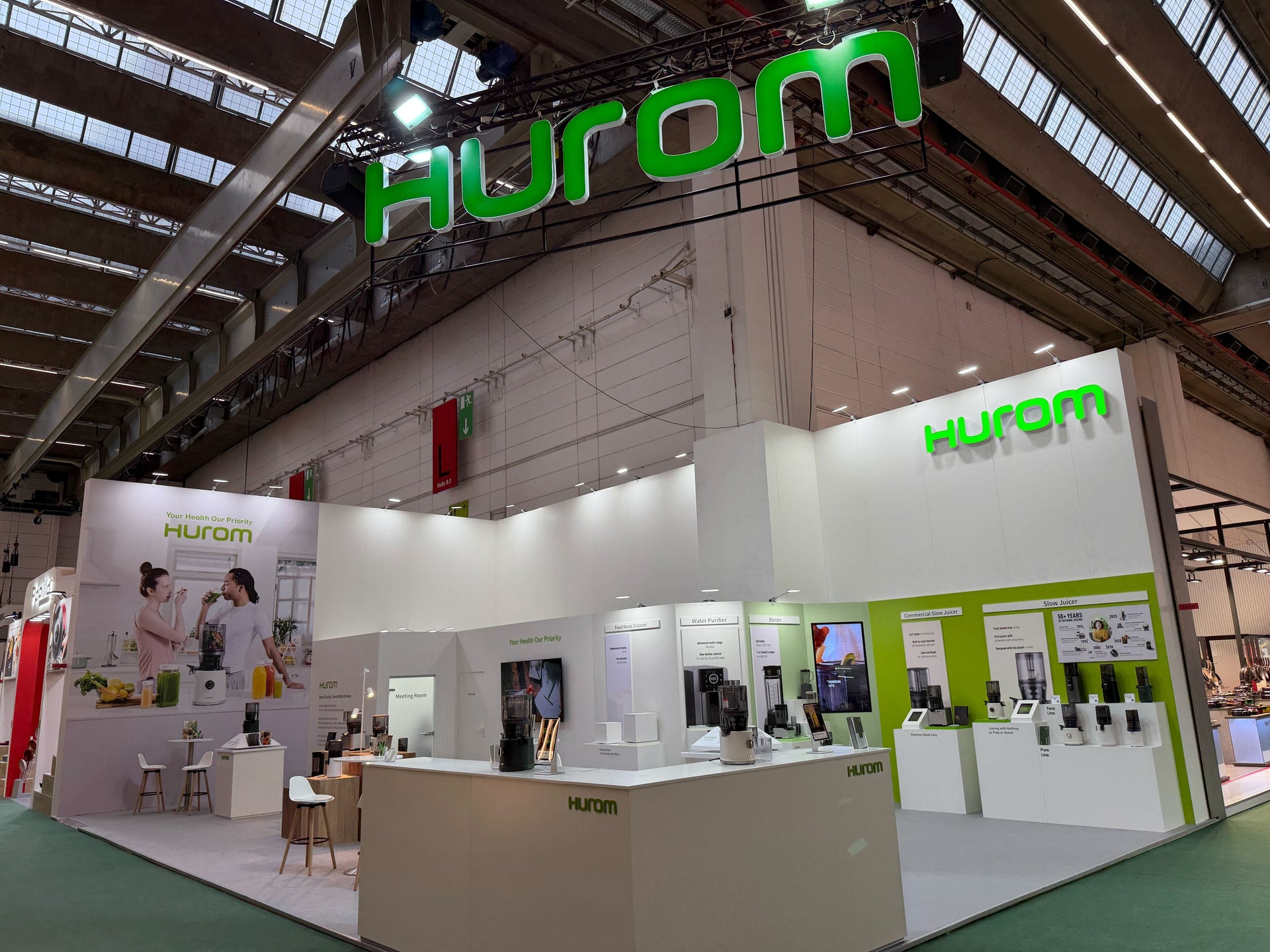 Hurom booth display at an indoor exhibition with products and signage